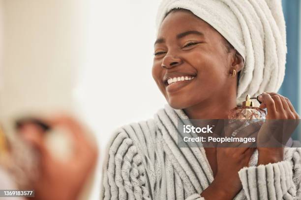 Shot Of A Young Woman Looking Cheerful While Using Perfume Stock Photo - Download Image Now