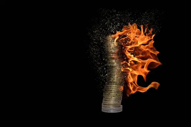 Photo of stack of many burning coins decomposes and dissolves due to inflation with black