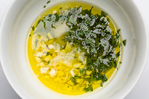 Sauce for fish with lemon,garlic, olive oil and parsley photographed in white bowl on white