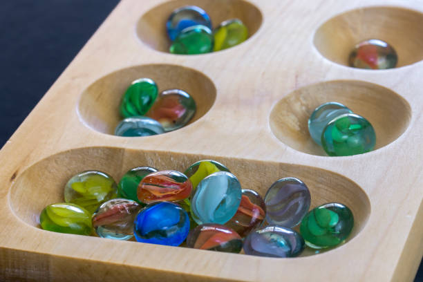 istock Mancala board and marbles on black background 1369186709