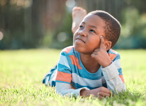 снимок маленького мальчика, лежащего на траве снаружи - clothing image type childhood nature стоковые фото и изображения