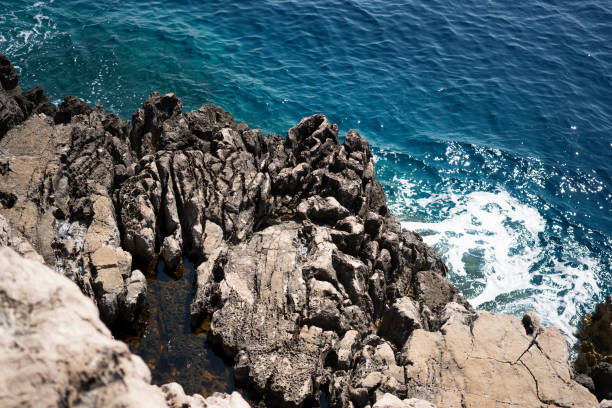 Agua azul del océano con olas rompiendo en la costa rocosa - foto de stock