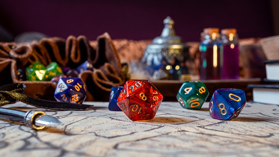 Close-up image of a red 20-sided role-playing gaming on brown paper within the background a leather dice bag and magic potions