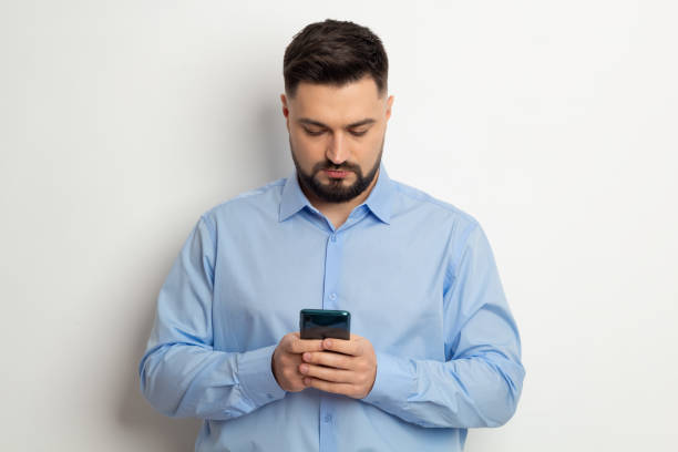 istock Portrait of a man using a mobile phone, smartphone standing on a white background. 1369191385