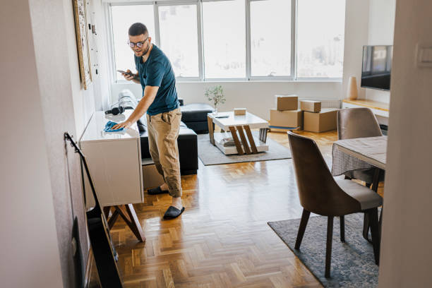 istock Shot of a handsome young man cleaning his home while using his smart phone 1369191851