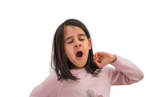 Little girl yawns on a white background