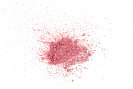 A pile of a sample of pink dry dye or powder on a white background.