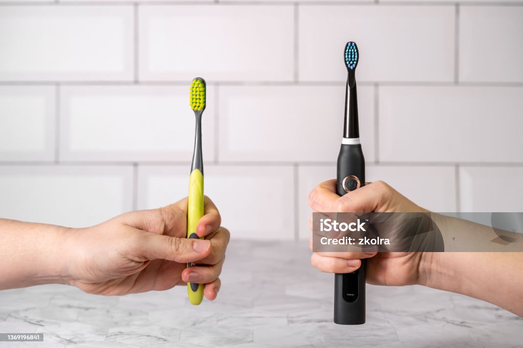 Electric and regular toothbrush in a bathroom. Dental care. Manual toothbrush against modern electric toothbrush concept. Toothbrush Stock Photo