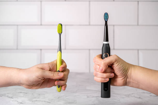 electric and regular toothbrush in a bathroom. dental care. manual toothbrush against modern electric toothbrush concept. - escovar imagens e fotografias de stock