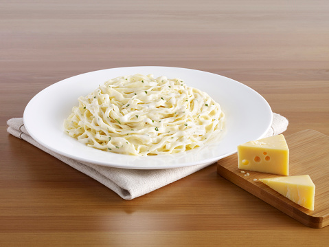 Delicious pasta plate and cheese blocks on a wooden table