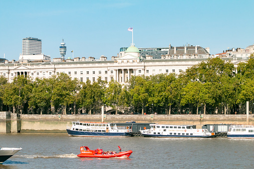Somerset House on Embankment in City of Westminster, London, with people on an inflatable boat in the foreground.