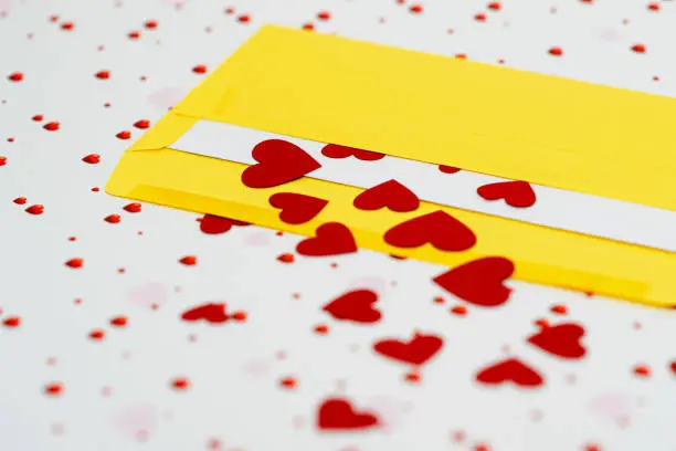 Red little hearts coming out from yellow envelope on valentine day background with copy space, loveletter concept, close-up