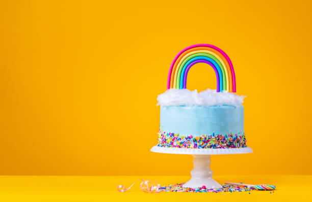 istock Blue Birthday Cake with Rainbow topper on Yellow 1369199287