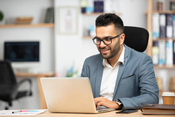 porträt eines gutaussehenden jungen geschäftsmannes, der im büro arbeitet - desk men sitting computer stock-fotos und bilder