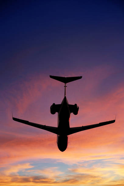 corporate jet airplane in silhouette flying at sunset, vertical frame