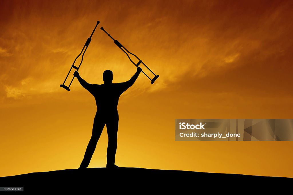 XXL triumphant disabled man man in silhouette holding up underarm crutches at sunrise (XXL) Applauding Stock Photo