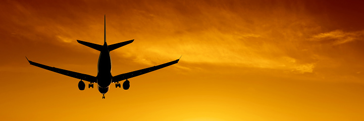 jet airplane in silhouette landing at sunset, panoramic frame (XXL)