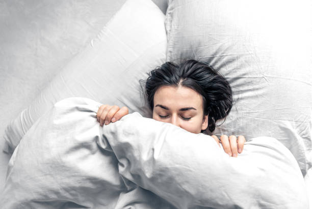 istock A beautiful young woman sleeps in a white bed. 1369203527