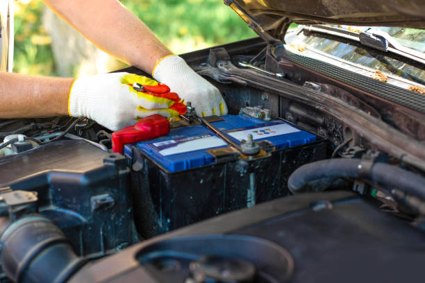 un uomo svita un supporto per la batteria di un'auto. riparazione e sostituzione della batteria - battery replacement foto e immagini stock