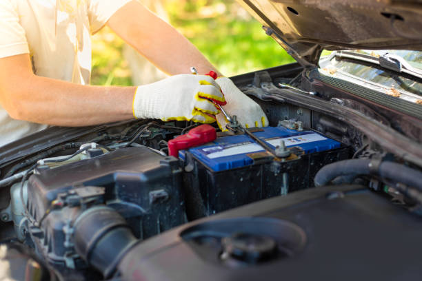 한 남자가 자동차 배터리 마운트를 풀고 있습니다. 배터리 수리 및 교체 - battery replacement 뉴스 사진 이미지