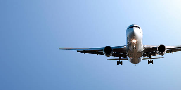 jet avión aterrizando en cielo azul - aterrizar fotografías e imágenes de stock