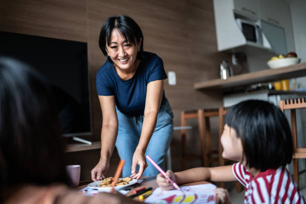 istock Mother serving cookies to daughters drawing at home 1369205788