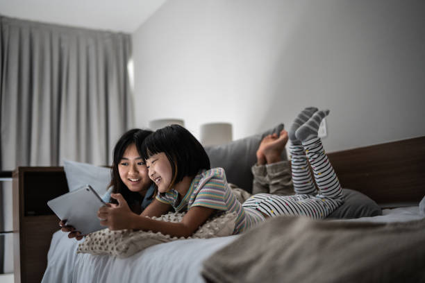 Sisters watching a movie on the digital tablet at home Sisters watching a movie on the digital tablet at home asian kids watching tv stock pictures, royalty-free photos & images