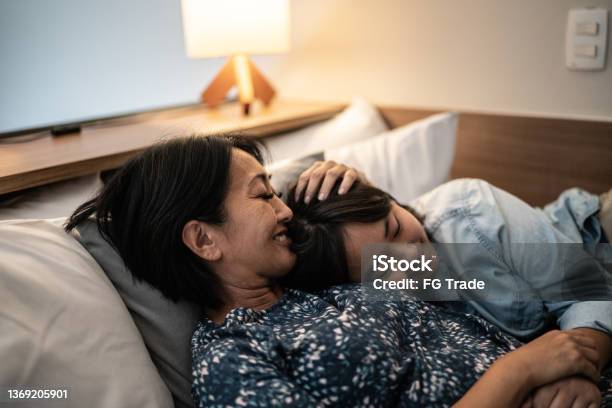 自宅でベッドに娘と横たわる母親
