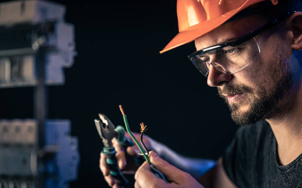 un elettricista maschio lavora in un centralino con un cavo di collegamento elettrico. - elettricista foto e immagini stock