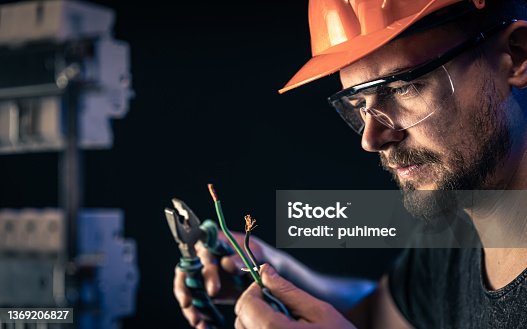 istock A male electrician works in a switchboard with an electrical connecting cable. 1369206827