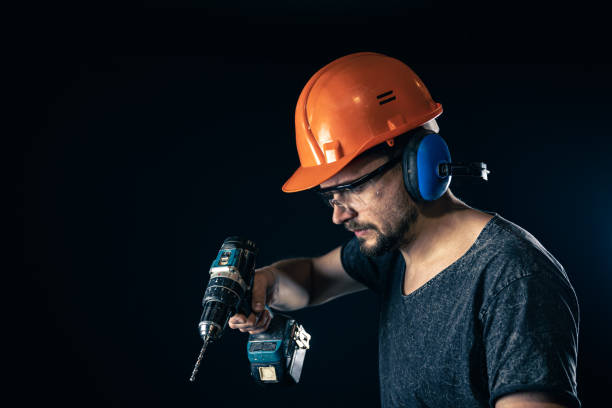 istock A young man in overalls protective helmet hard hat hold electric drill. 1369206832