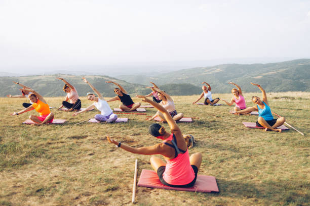 istock Big group of women going yoga class outdoors on a hill 1369207341