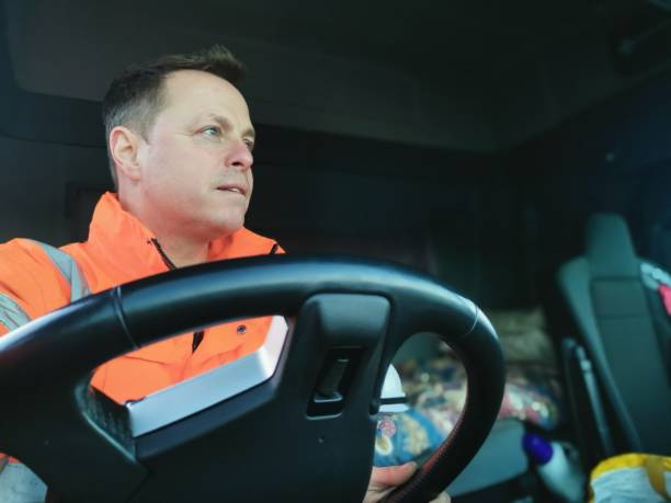 Male Truck Driver interior Portrait Middle Aged Male Truck Driver Wearing a High Visibility Jacket and holding the Vehicle Steering Wheel driver occupation stock pictures, royalty-free photos & images