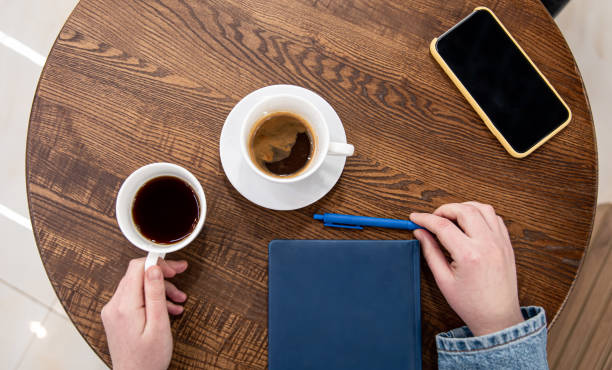 istock A cup of coffee on a wooden table and a notepad, top view. 1369208502