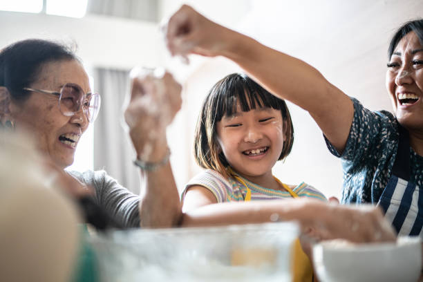 happy family making mess while preparing a cake at home - grandmother cooking baking family imagens e fotografias de stock