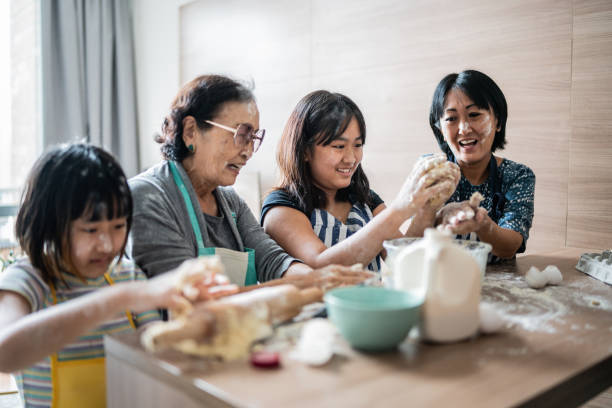 glückliche familie, die unordnung macht, während sie zu hause einen kuchen zubereitet - togetherness learning playful mother stock-fotos und bilder