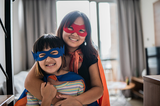 Portrait of sisters dressed as superheroes at home
