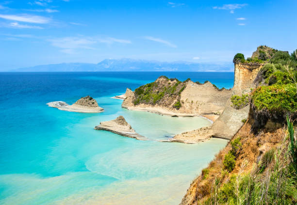 Cape Drastis cliffs near Sidari and Peroulades on Corfu island in Greece. Famous rock formations with small beach and rugged coastline. Popular Greek destination for summer vacation. Cape Drastis cliffs near Sidari and Peroulades on Corfu island in Greece. Famous rock formations with small beach and rugged coastline. Popular Greek destination for summer vacation corfu stock pictures, royalty-free photos & images