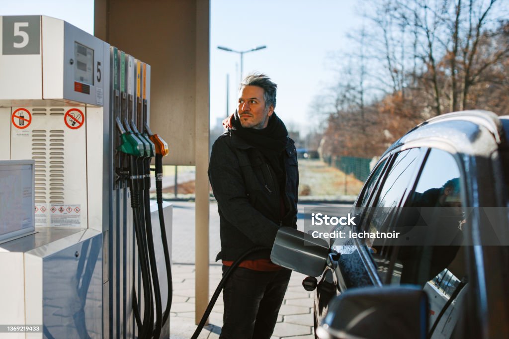 man filling a tank with fuel at the gas station in Berlin Man filling a tank with fuel at the gas station in Berlin, Germany. He is still using the Diesel engine on the modern car, providing much more range for long trips than the current electrical vehicles. Refueling Stock Photo