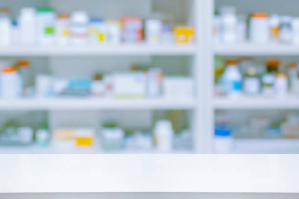 istock Empty white counter with pharmacy drugstore shelves blurred background 1369223969