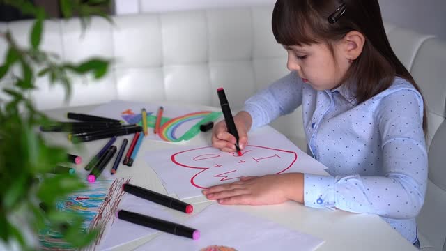 Child draws hearts on paper with pink markers. Children's creativity. St. Valentines day, happy family