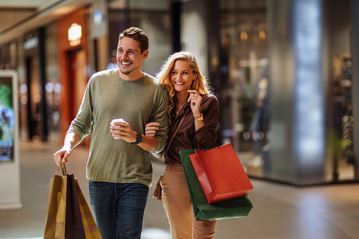 Smiling young couple walking through the mall after some shopping