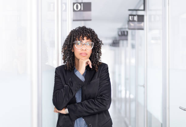 istock Brown skin woman standing on a office hall thinking 1369232248