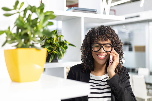 istock Caribbean curly woman talking on a cellphone at office smiling 1369232263
