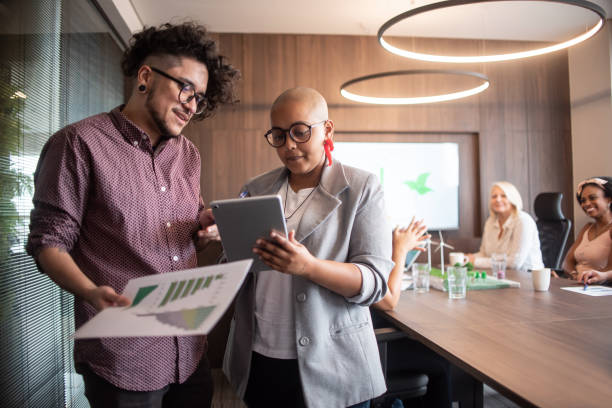 Businesspeople talking - including a trans man Businesspeople talking - including a trans man using tablet transgender person in office stock pictures, royalty-free photos & images