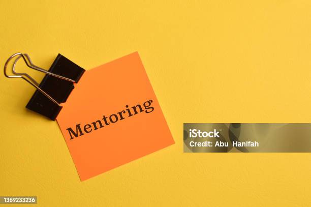 Orange Paper Written With Text Mentoring Isolated On Yellow Background Stock Photo - Download Image Now
