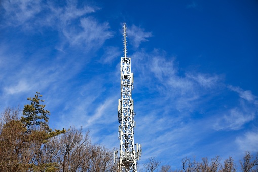 Silver radio tower towering in the blue autumn sky