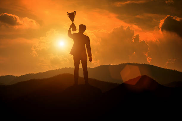 istock Silhouette of a businessman holding a trophy 1369244585