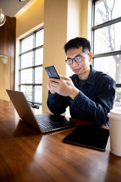 istock Young man working with mobile phone at cafe 1369247606