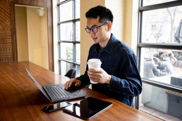 istock Man working and holding a cup of coffee at cafe 1369247651
